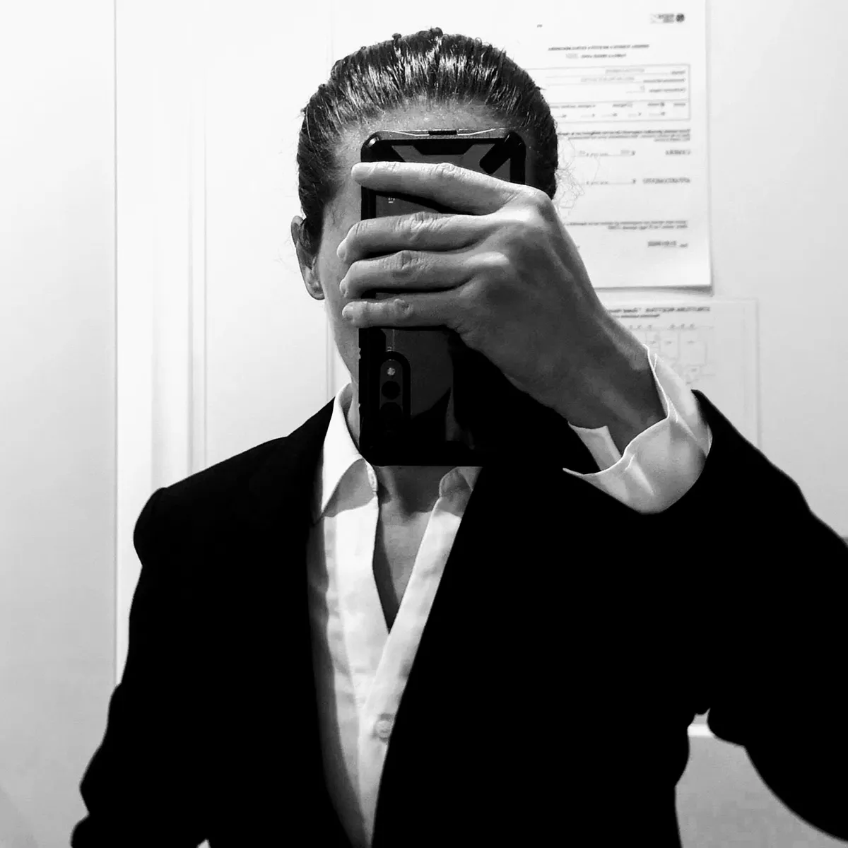 Ornella Pesenti, in giacca, si fotografa allo specchio dietro il telefono